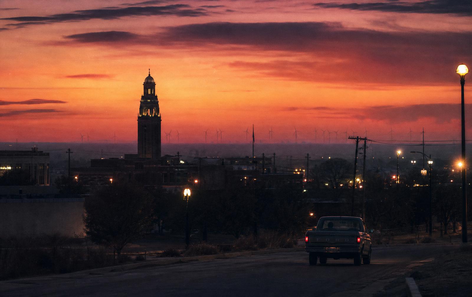 Lubbock, Texas skyline at dusk with the Texas Tech bell tower and wind turbines on the horizon